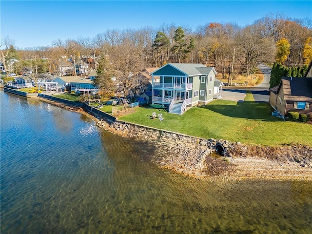 rear view of property with a water view, a balcony, and a lawn