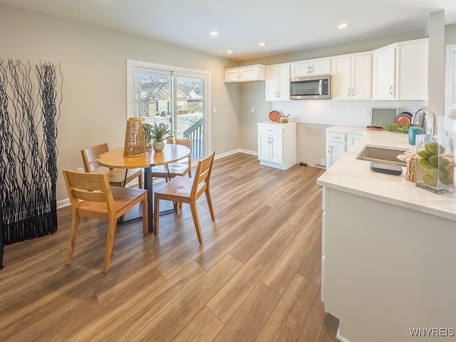 kitchen with backsplash, sink, light hardwood / wood-style flooring, and white cabinets