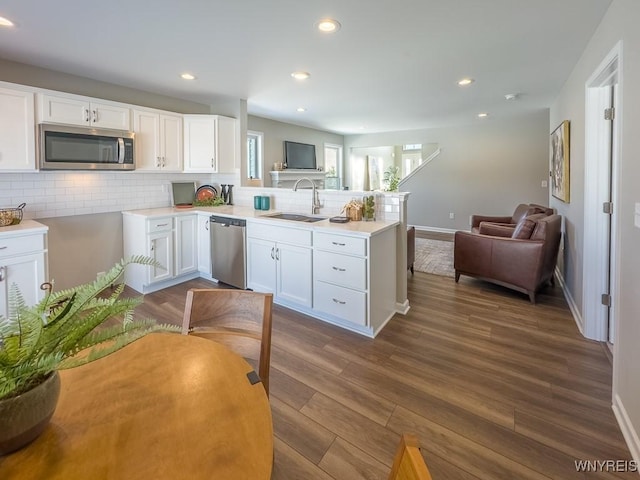 kitchen featuring sink, tasteful backsplash, appliances with stainless steel finishes, kitchen peninsula, and white cabinets