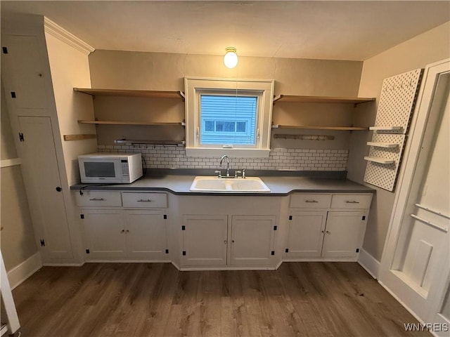 kitchen featuring dark hardwood / wood-style floors, white cabinetry, tasteful backsplash, and sink