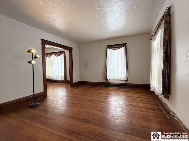 spare room featuring a textured ceiling and dark hardwood / wood-style floors