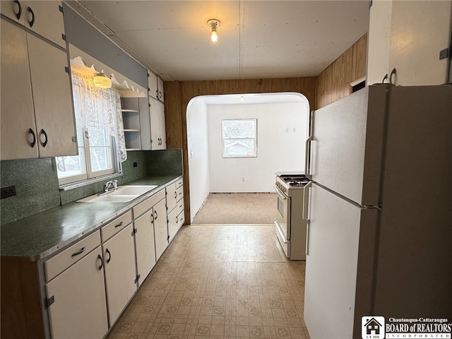 kitchen featuring white cabinetry, sink, tasteful backsplash, stainless steel range with gas cooktop, and white refrigerator