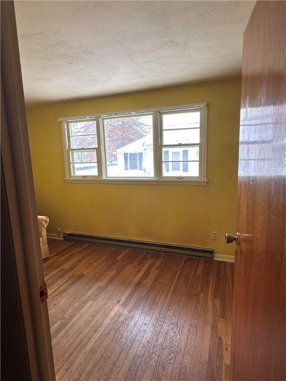 spare room featuring a baseboard radiator, a textured ceiling, and wood-type flooring