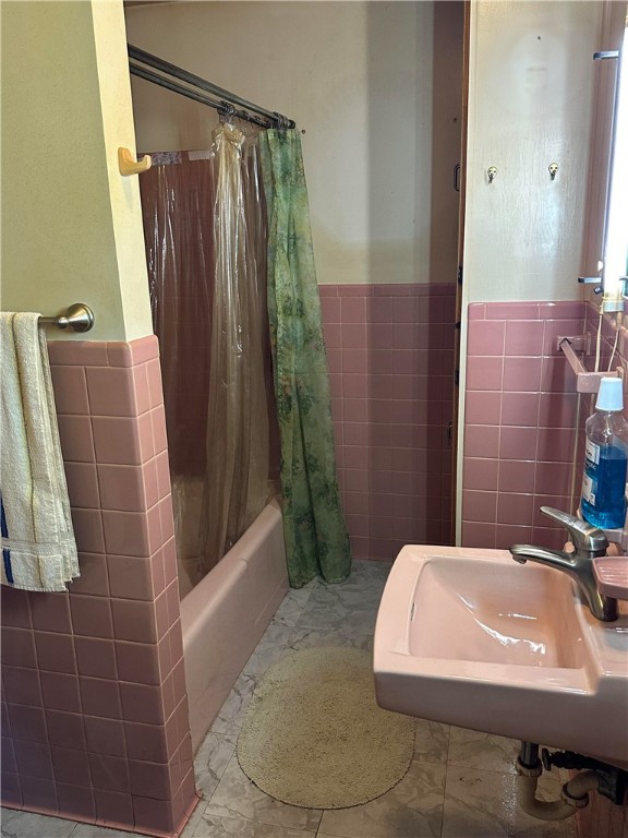 bathroom featuring shower / bath combo, tile walls, and sink