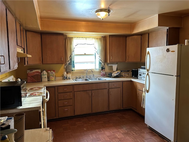 kitchen featuring white refrigerator, dark parquet flooring, and sink