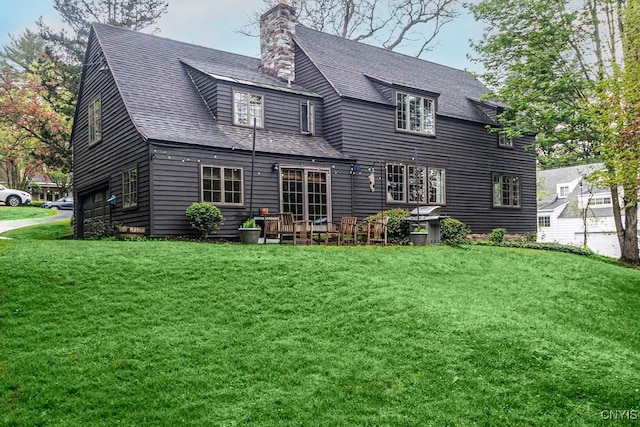 rear view of property featuring a garage and a lawn