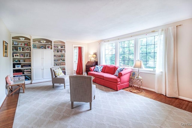 living room with built in shelves and light wood-type flooring