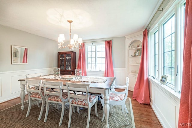 dining space with built in features, a chandelier, and dark hardwood / wood-style floors