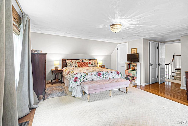 bedroom featuring wood-type flooring and vaulted ceiling