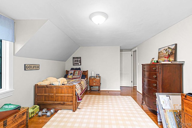 bedroom with multiple windows, lofted ceiling, and hardwood / wood-style flooring