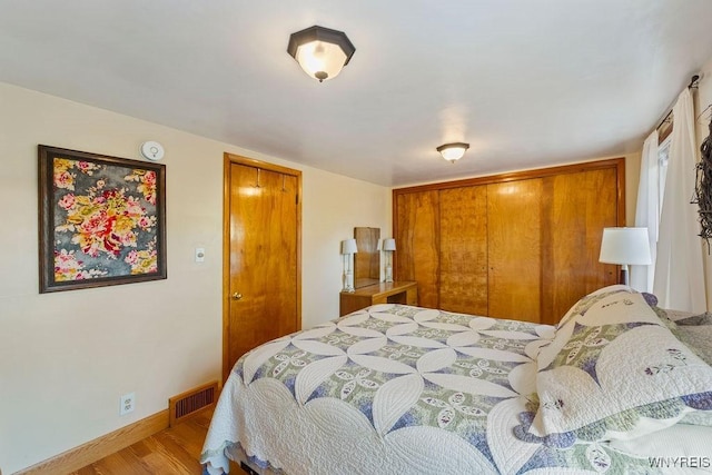 bedroom with light hardwood / wood-style floors and a closet