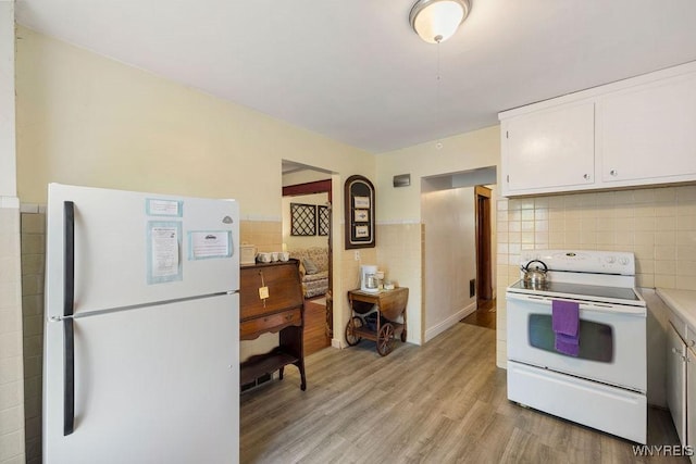 kitchen featuring white cabinetry, light wood-type flooring, and white appliances