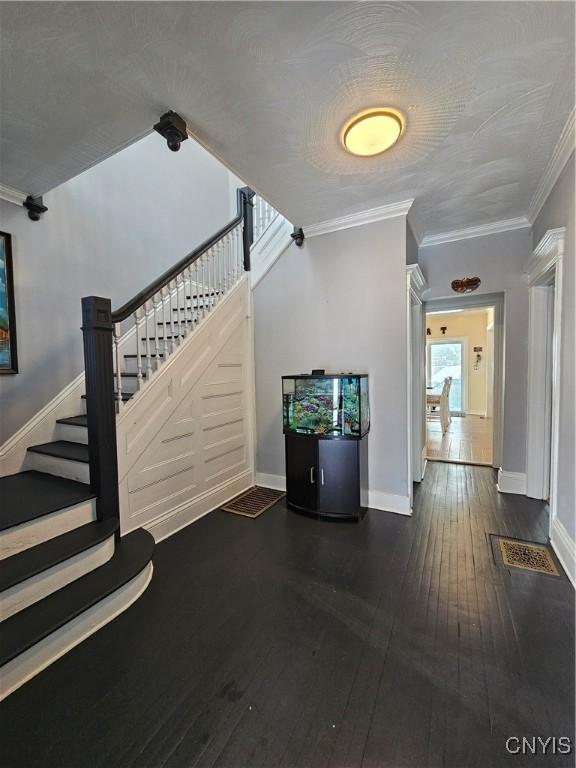 stairs with a textured ceiling, hardwood / wood-style flooring, and ornamental molding