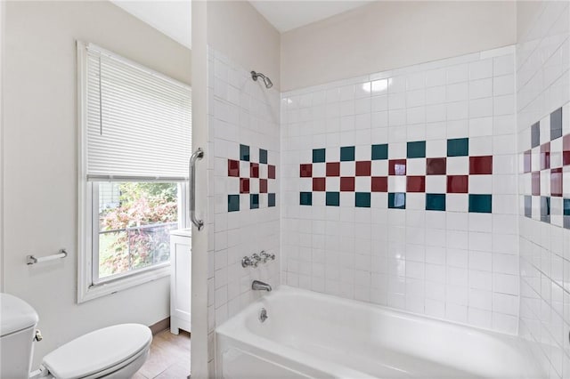 bathroom with toilet and tiled shower / bath