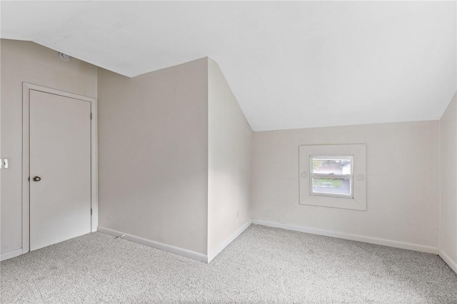 additional living space featuring light carpet and vaulted ceiling