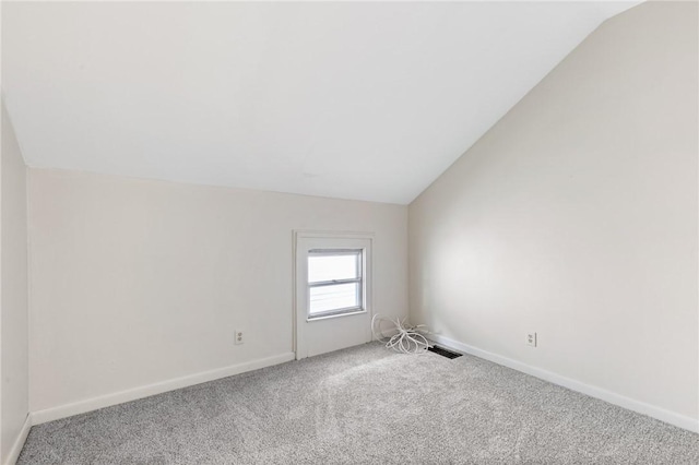 carpeted spare room featuring lofted ceiling