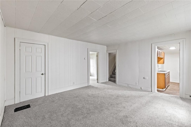 unfurnished bedroom with ensuite bathroom, sink, and light colored carpet