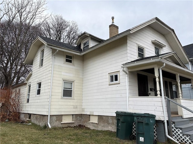 view of side of property with a yard and covered porch