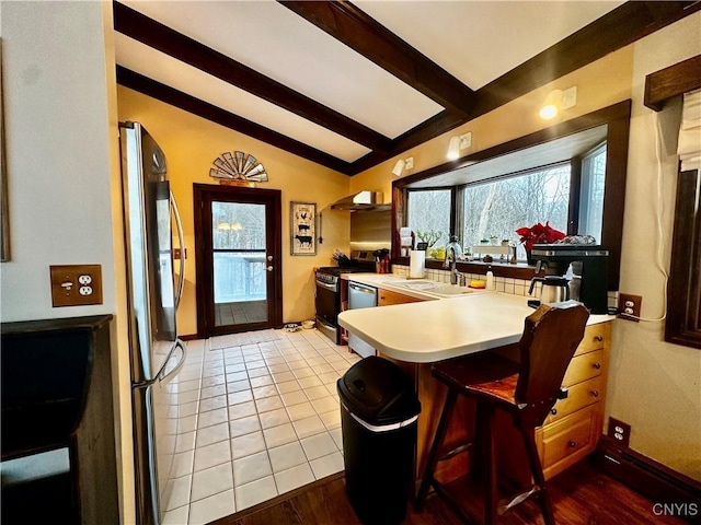 kitchen featuring a kitchen breakfast bar, stainless steel stove, lofted ceiling with beams, and fridge