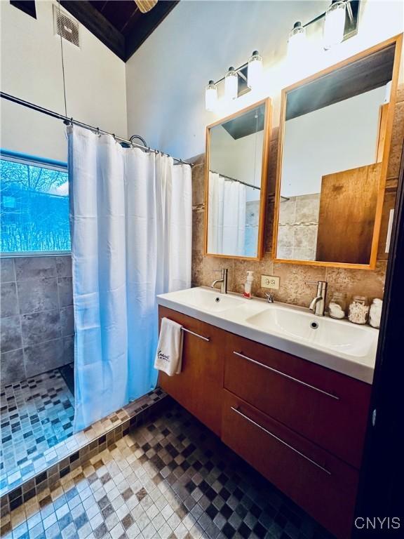 bathroom with a shower with curtain, vanity, and backsplash