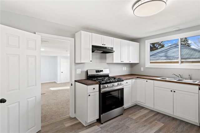 kitchen featuring wooden counters, light wood-type flooring, stainless steel gas range oven, sink, and white cabinetry