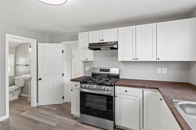 kitchen with stainless steel gas range oven, wooden counters, sink, light hardwood / wood-style flooring, and white cabinetry