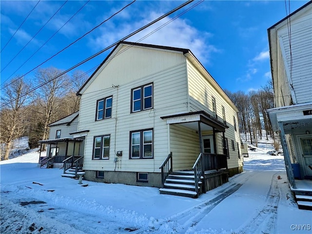 snow covered back of property featuring a porch