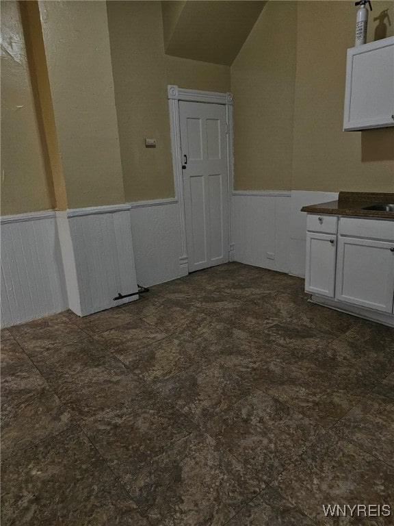 unfurnished dining area featuring sink and vaulted ceiling