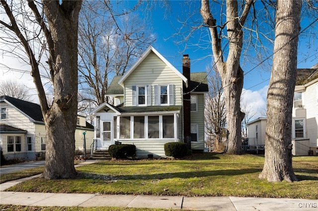 view of front of house with a sunroom and a front yard