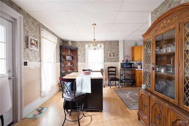 dining area featuring a drop ceiling, a chandelier, and light hardwood / wood-style flooring