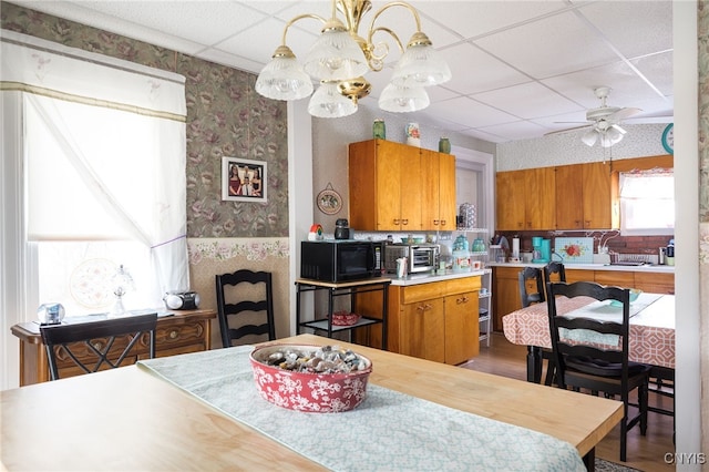 kitchen with ceiling fan, a drop ceiling, hardwood / wood-style floors, and decorative light fixtures