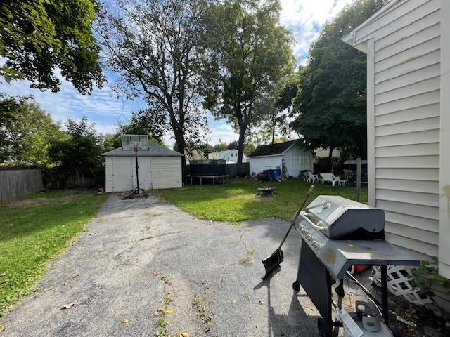 view of yard with a storage shed and a trampoline