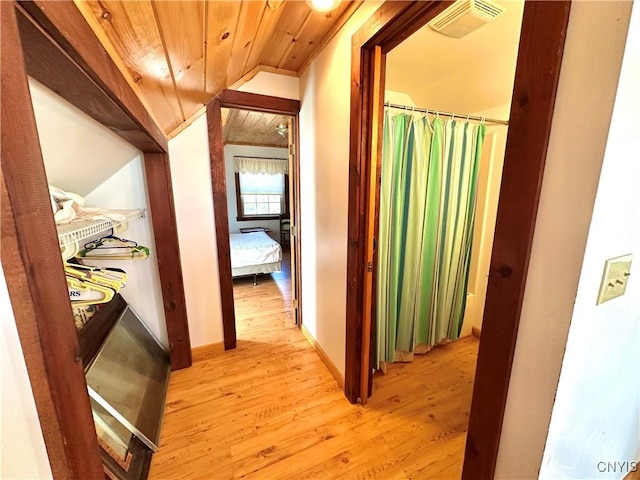 hallway featuring lofted ceiling, light hardwood / wood-style flooring, and wooden ceiling