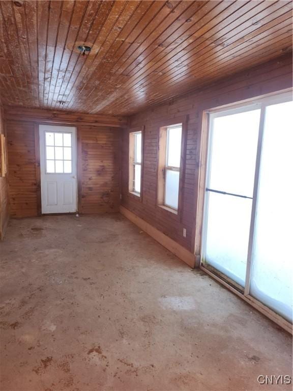 unfurnished room with a wealth of natural light, wooden ceiling, and wooden walls