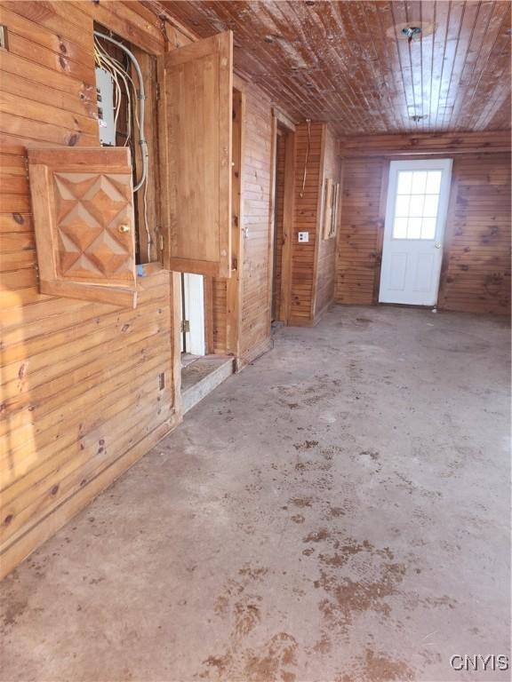 interior space with concrete floors, wooden ceiling, and wooden walls