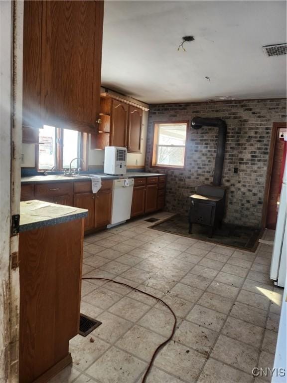 4057 Wilson Rd E, Annsville, NY 13471 - kitchen featuring a wood stove, white dishwasher, open shelves, brick wall, and a sink