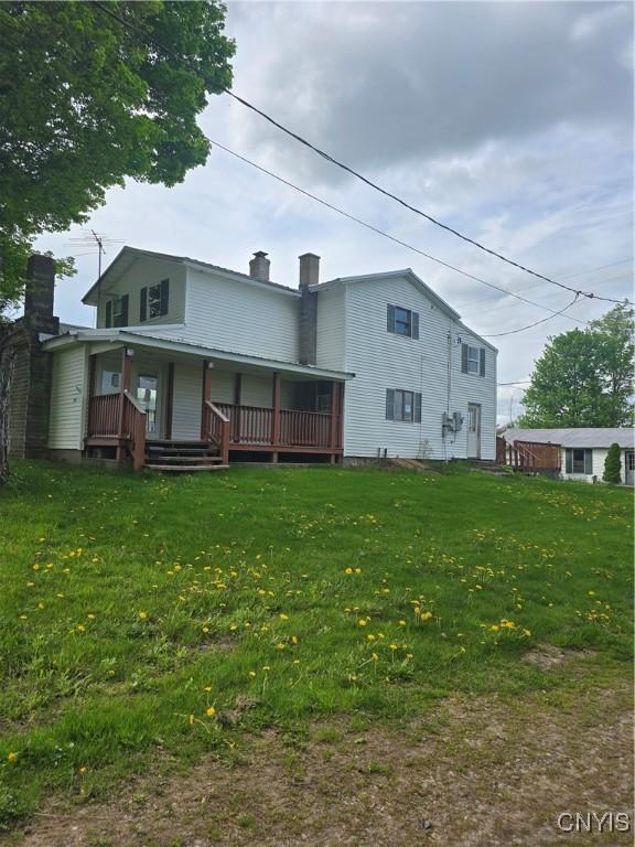 4057 Wilson Rd E, Annsville, NY 13471 - back of property featuring a chimney, covered porch, and a lawn