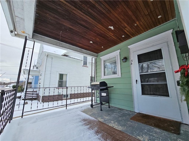 snow covered patio featuring a porch and grilling area