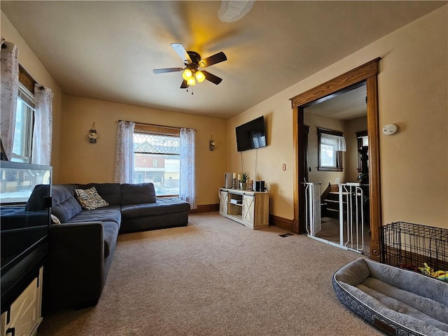 living room featuring a wealth of natural light, ceiling fan, and light colored carpet