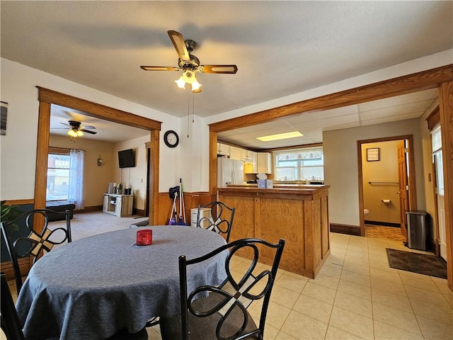 tiled dining space with ceiling fan and wood walls