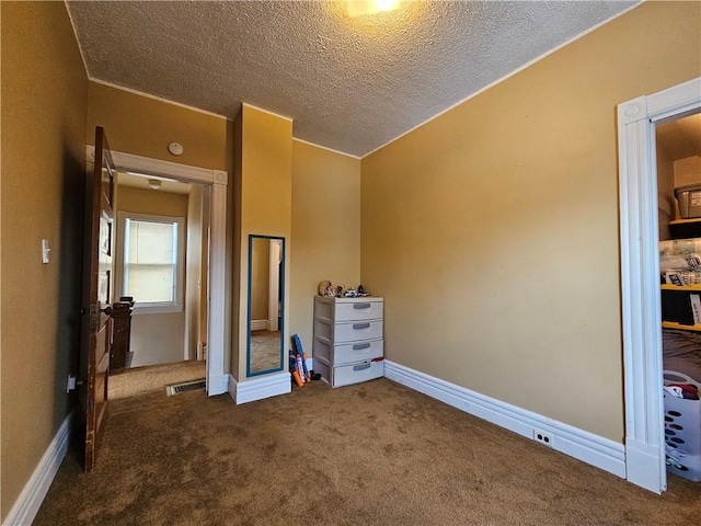 unfurnished bedroom with a textured ceiling and dark colored carpet