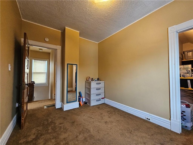 unfurnished bedroom with a textured ceiling and dark carpet