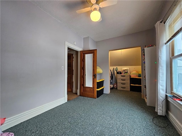 carpeted bedroom with multiple windows, ceiling fan, a closet, and a walk in closet