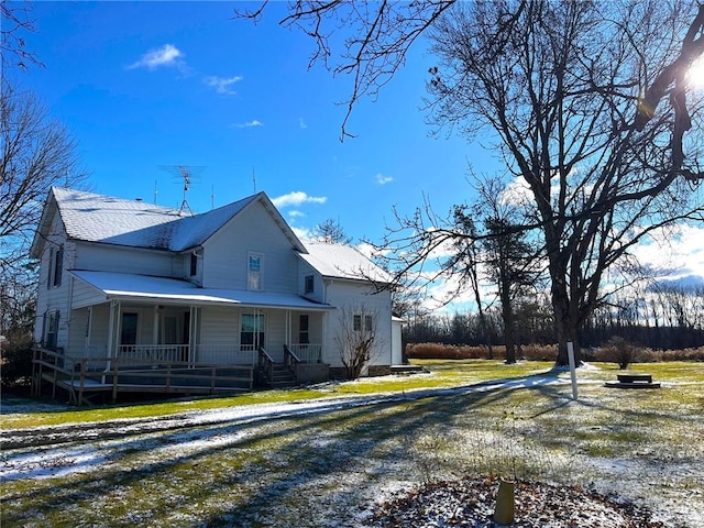 view of side of home featuring covered porch and a yard