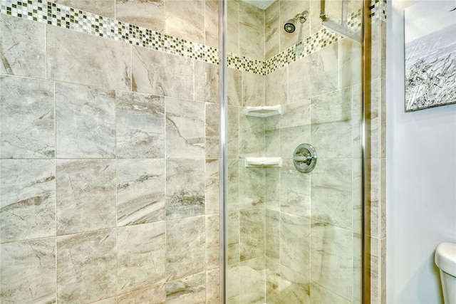 bathroom with a tile shower and toilet