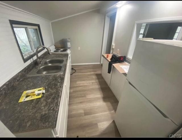 kitchen featuring white cabinetry, sink, dark stone countertops, crown molding, and light hardwood / wood-style floors