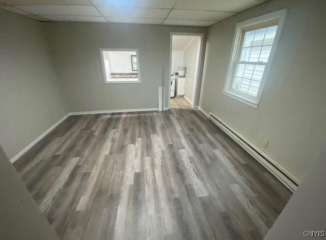 unfurnished room featuring a paneled ceiling, hardwood / wood-style flooring, and a baseboard radiator