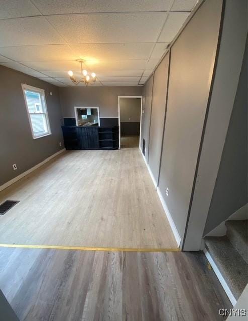 unfurnished living room featuring wood-type flooring and an inviting chandelier