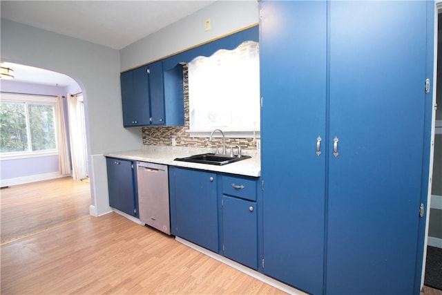 kitchen featuring blue cabinetry, dishwasher, sink, decorative backsplash, and light wood-type flooring