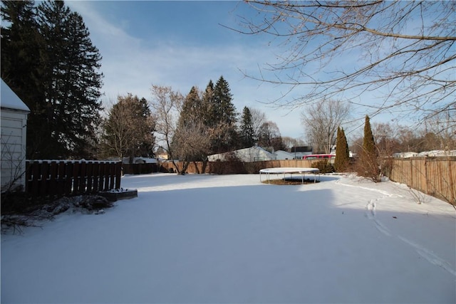 yard layered in snow with a trampoline